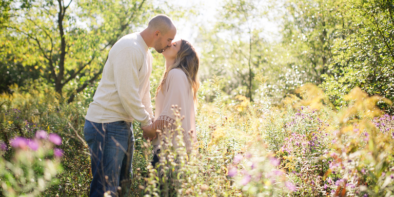 engaged couple kissing in a meadow